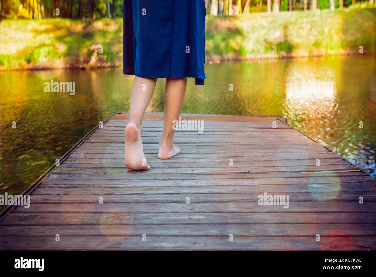 Ragazza adolescente facendo un passo bootlessly sul molo in legno e lo spostamento in avanti per l'acqua, il nuovo concetto di opportunità. messa a fuoco selettiva. Foto Stock