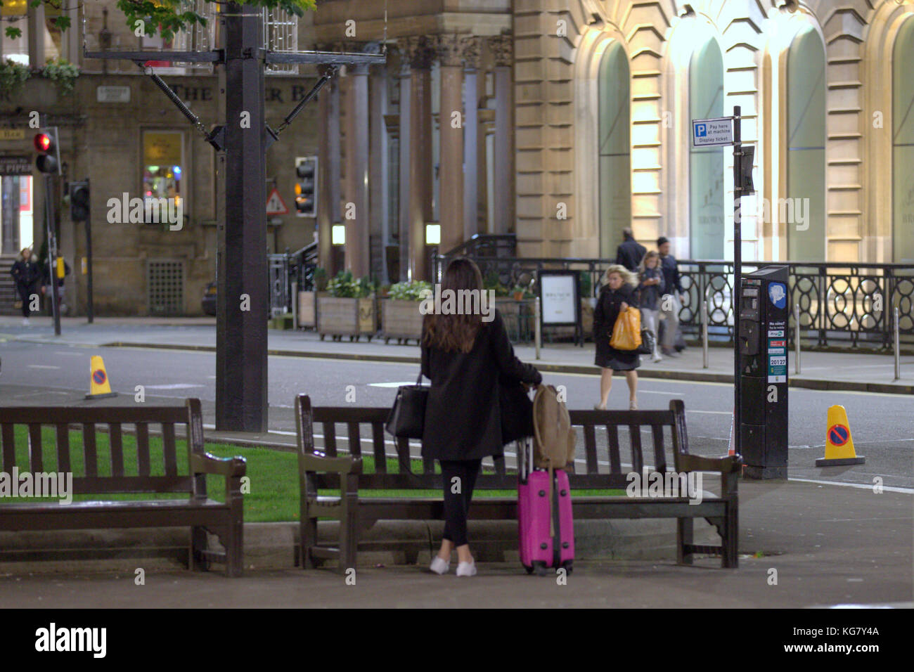 Ragazza donna al telefono in attesa del suo amico turista con custodie e borse viste da dietro George Square, Glasgow, Glasgow City, Regno Unito Foto Stock
