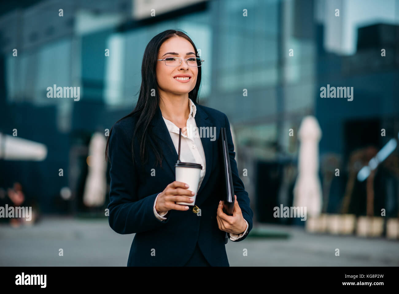 Business Woman in bicchieri con caffè in mani, contro il grattacielo. Edificio moderno centro finanziario, cityscape. successo imprenditore femmina Foto Stock