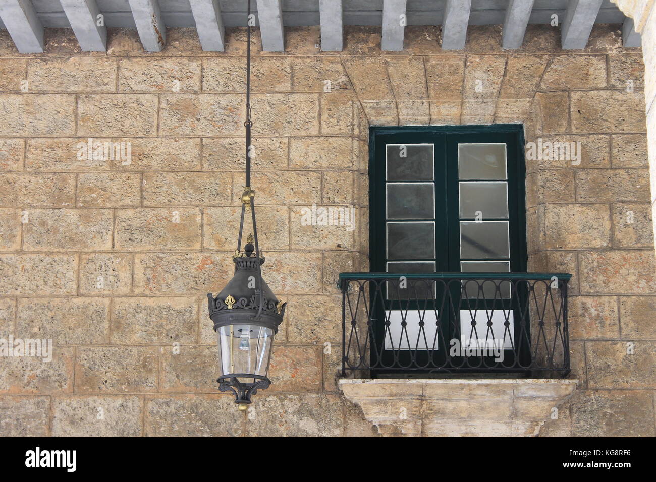 Porte con apertura verso un balcone di Giulietta in una parete di pietra in un vecchio stile spagnolo edificio, Avana, Cuba. Una lanterna pende dal soffitto. Foto Stock