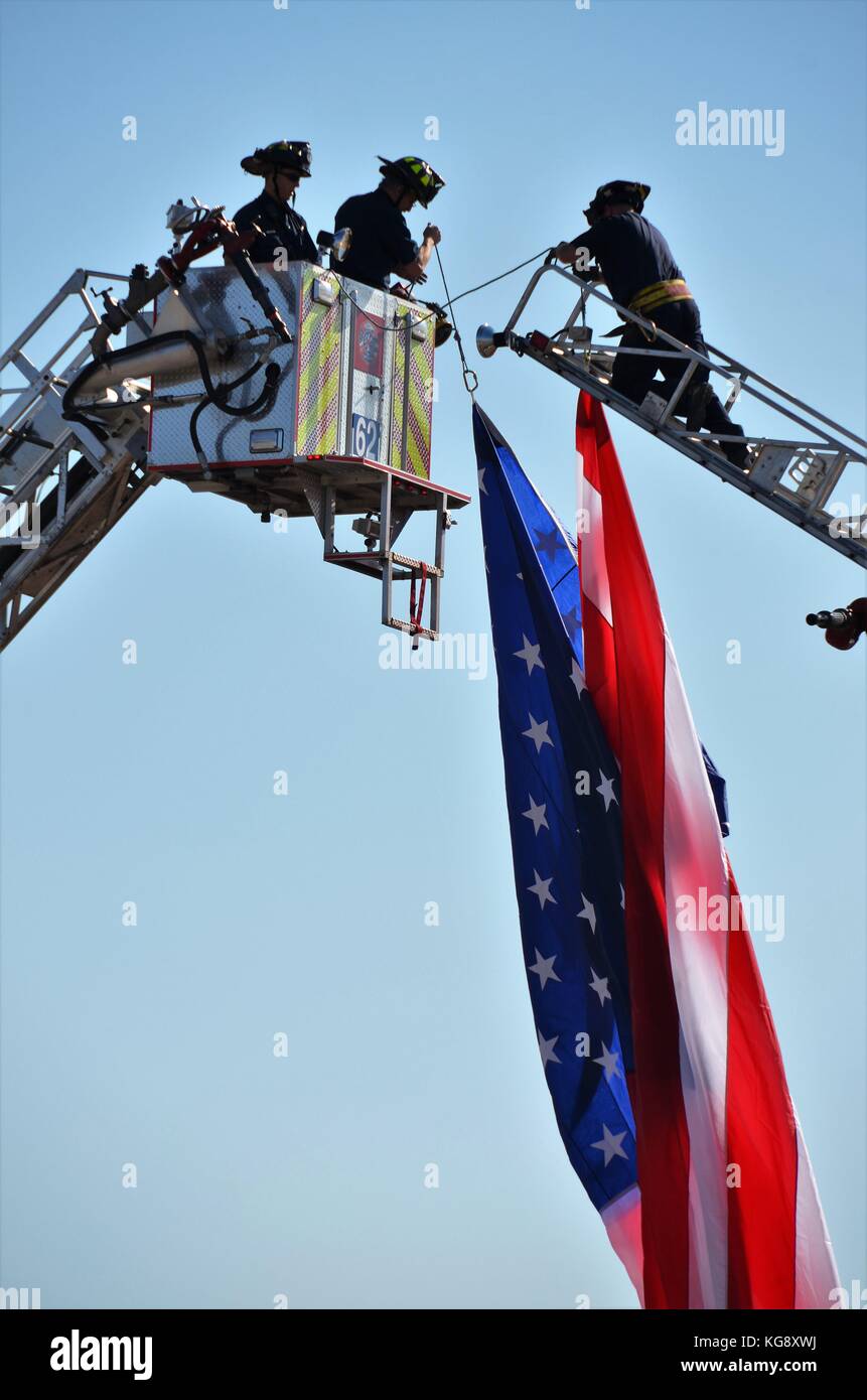 I vigili del fuoco appesa una bandiera americana tra loro camion fuoco Foto Stock