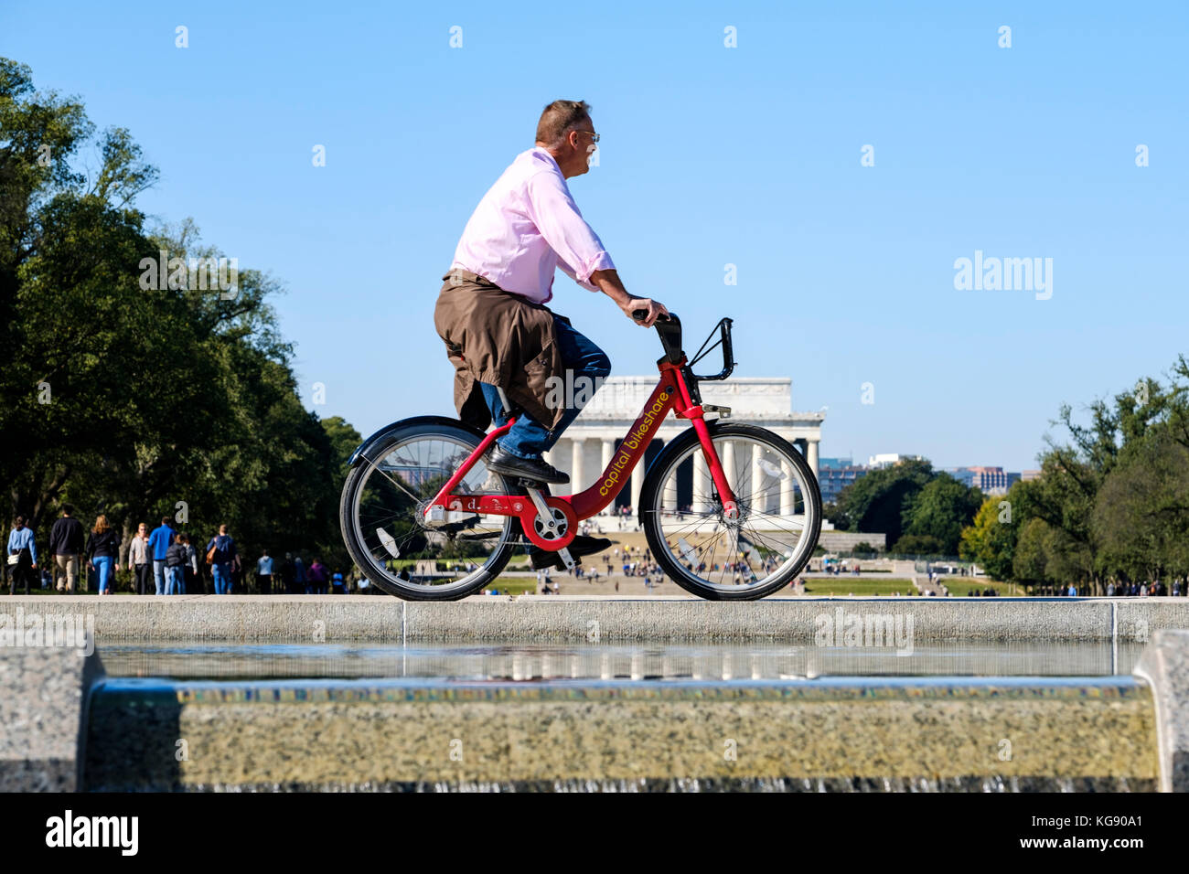 Ciclista maschile in sella a una bicicletta Capital Bikeshare, Abraham Lincoln Memorial in the background, Washington, DC, Stati Uniti d'America, USA. Foto Stock