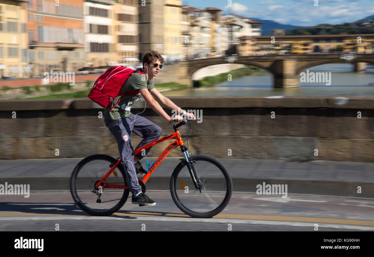 I giovani su una bicicletta rossa a cavallo su un ponte di Firenze contro lo sfondo di ponte vecchio Foto Stock