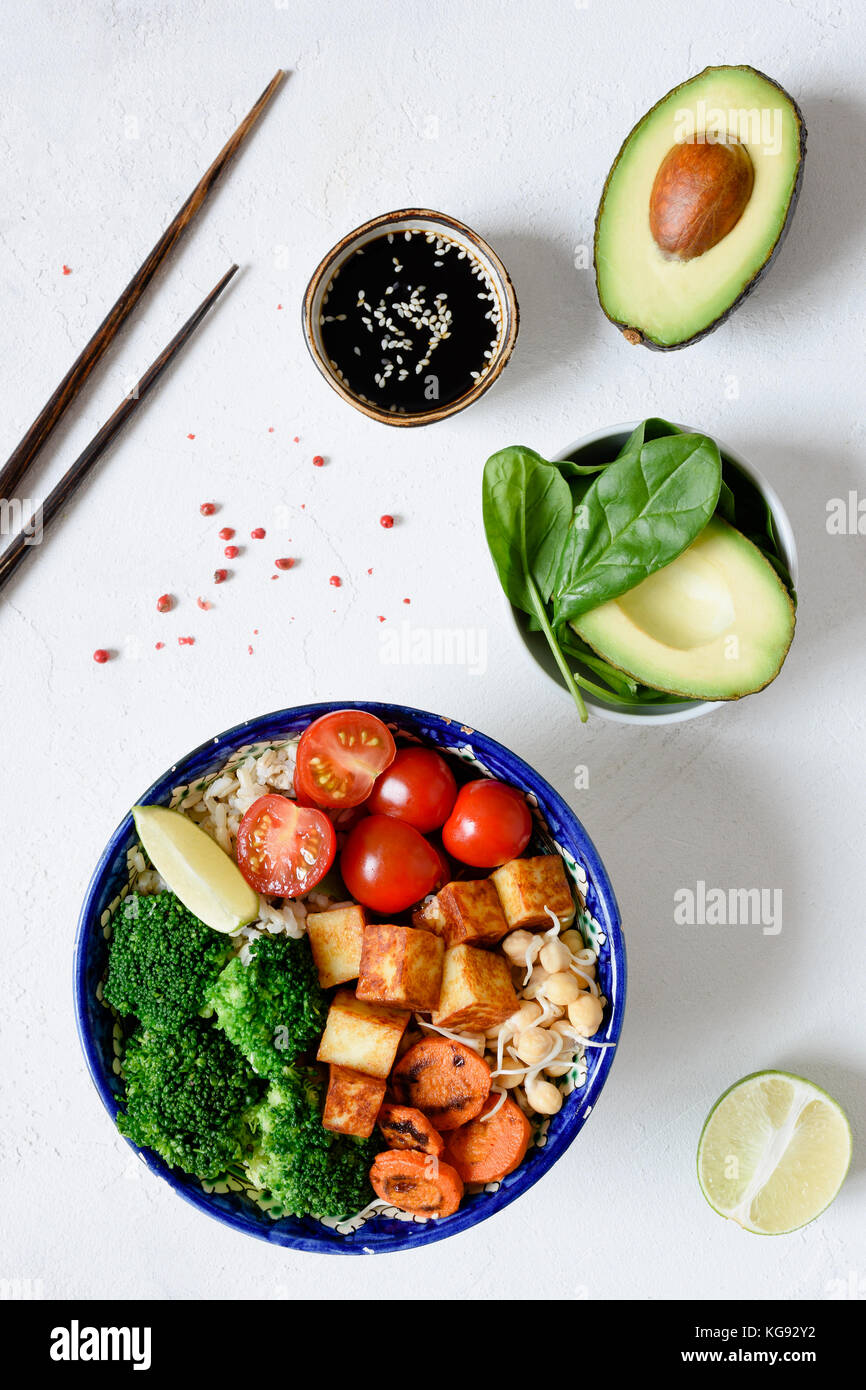 Ciotola di Buddha sana insalata vegetariana con broccoli, riso selvatico, tofu, carota, avocado, germoglio ceci e pomodoro ciliegino su sfondo bianco. Asian cui Foto Stock