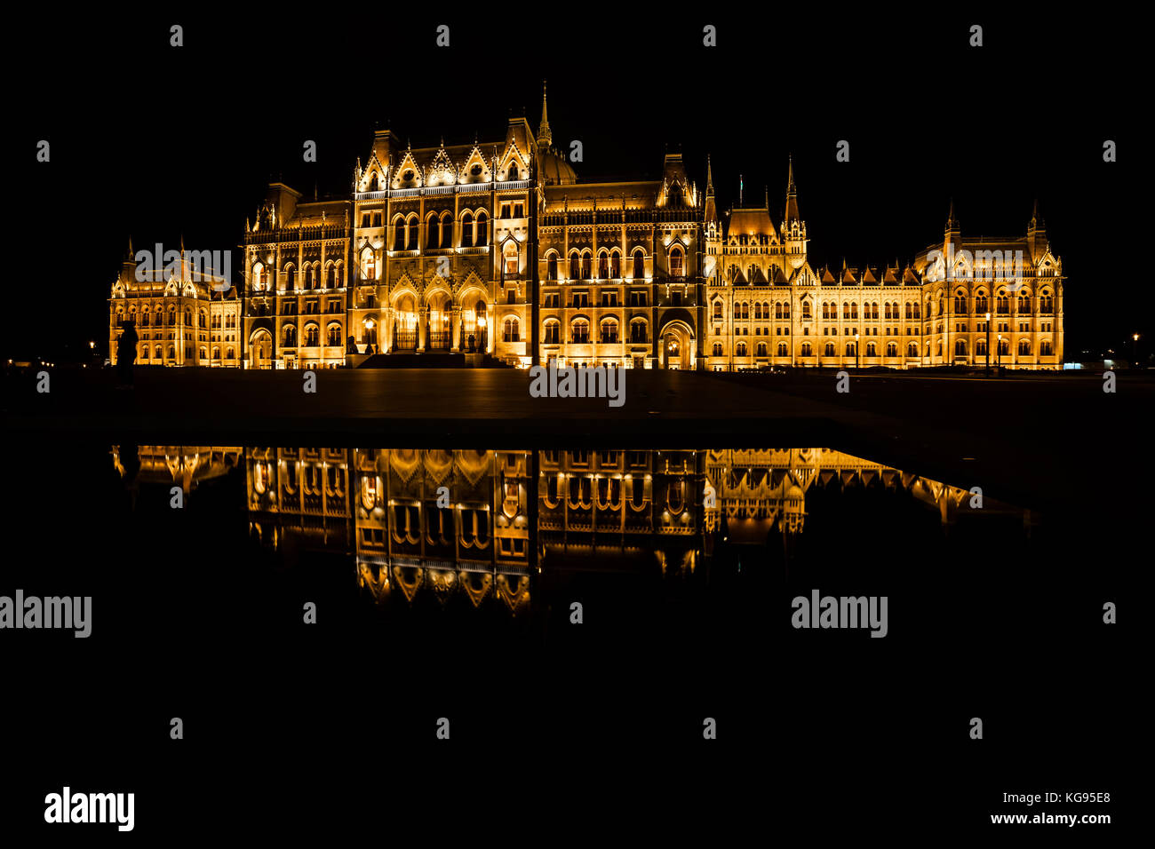 Ungheria, Budapest, ungherese il palazzo del parlamento è illuminato di notte con un riflesso speculare in acqua Foto Stock
