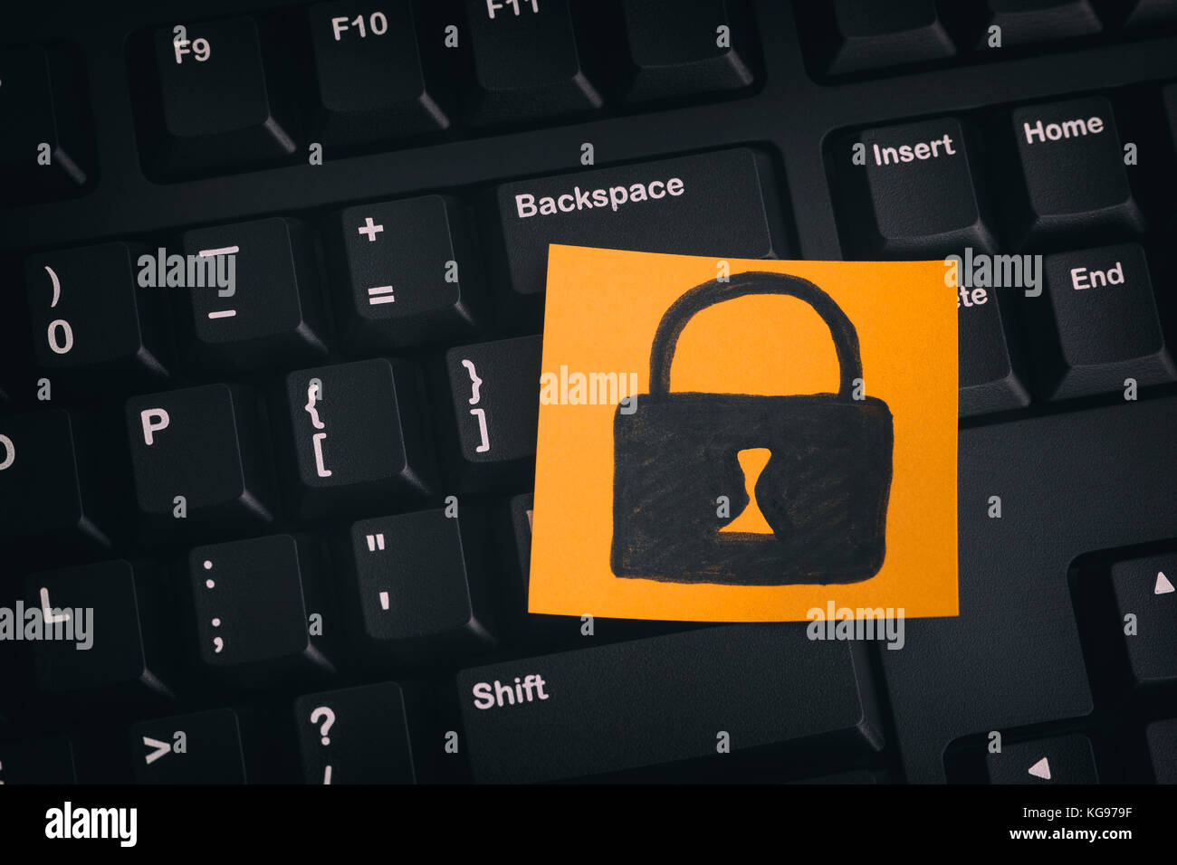 Sicurezza dei dati concetto. carta gialla nota con lucchetto chiuso su una tastiera nera. close up. Foto Stock