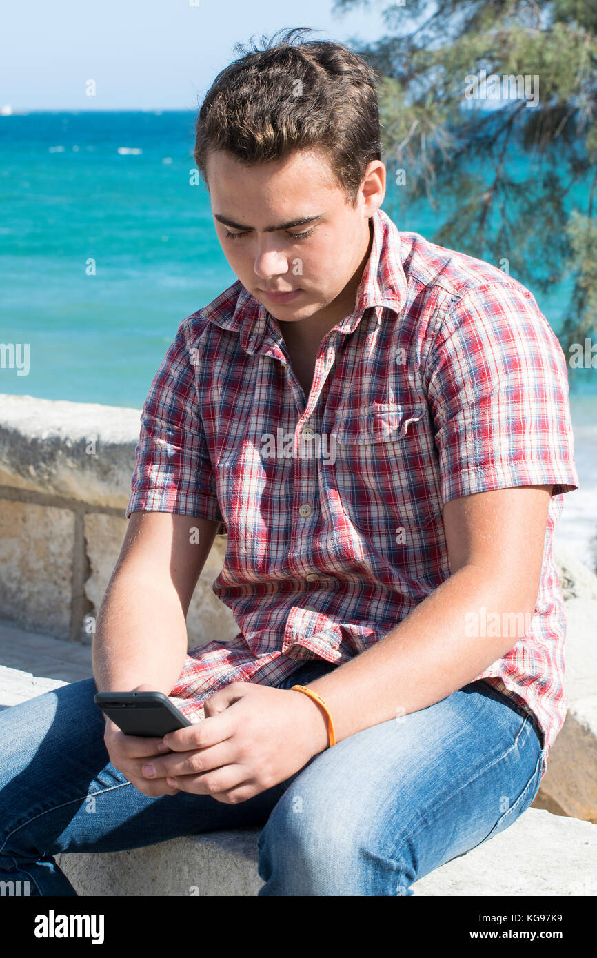 Goodlooking giovane uomo su telefono cellulare, dal mare, Mallorca, Spagna Foto Stock