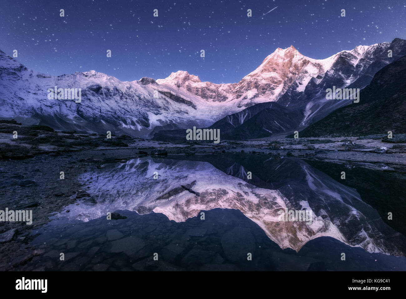 Incredibile scena notturna con himalayan montagne e lago di montagna alla notte stellata in Nepal. paesaggio con alte rocce a picco innevato e il cielo con le stelle Foto Stock