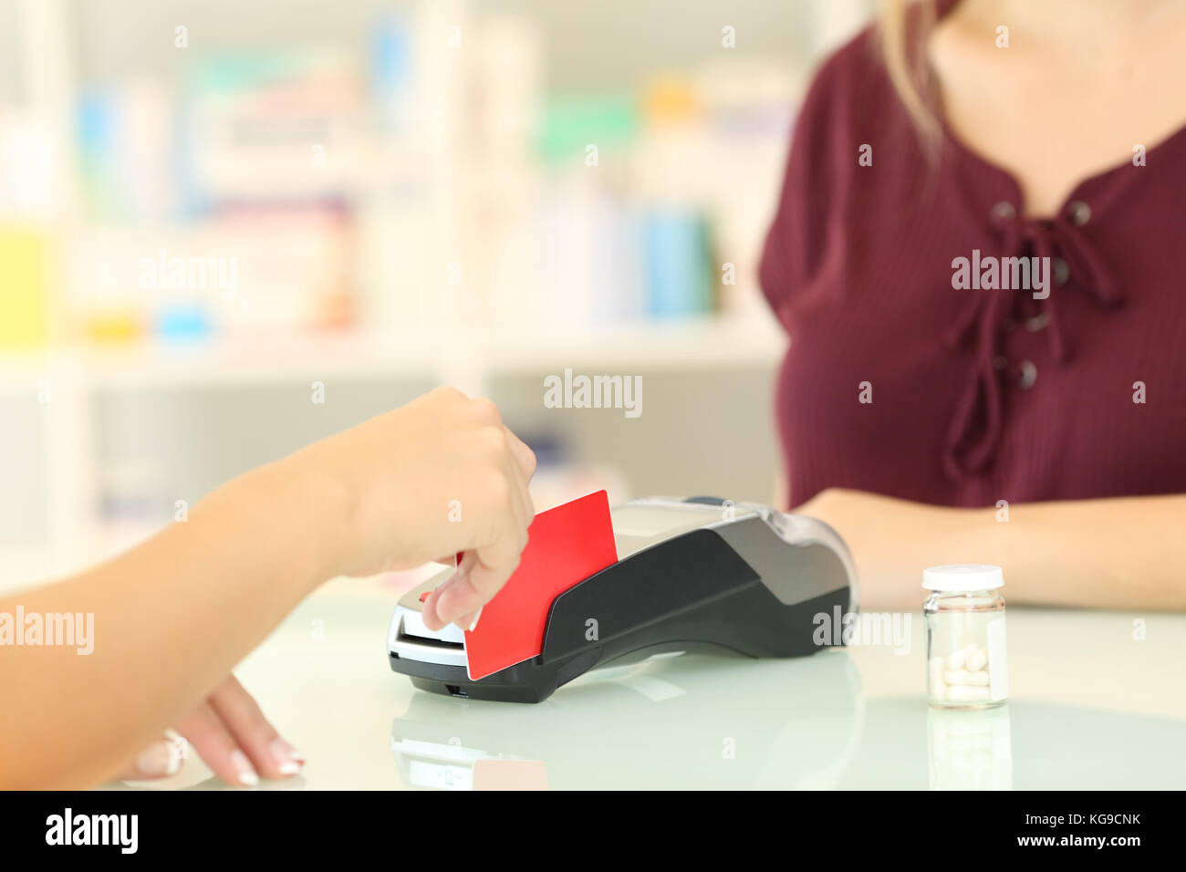 Close up di un farmacista di ricarica a mano con carta di credito su un contatore in una farmacia Foto Stock