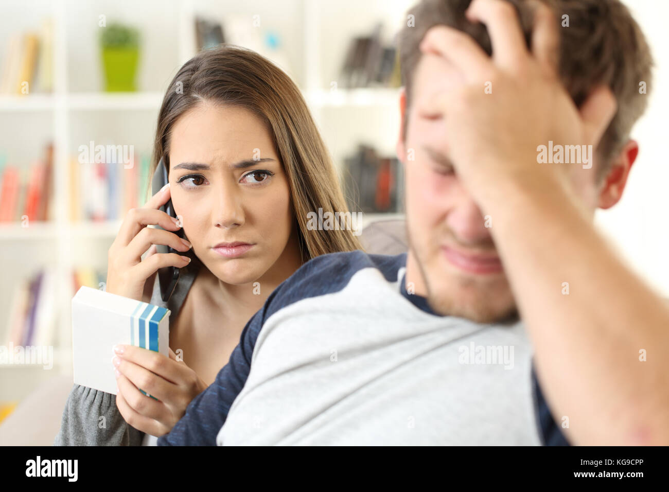 Preoccupato moglie chiamando medico chiedendo informazioni seduta su un divano nel soggiorno in un interno di una casa Foto Stock