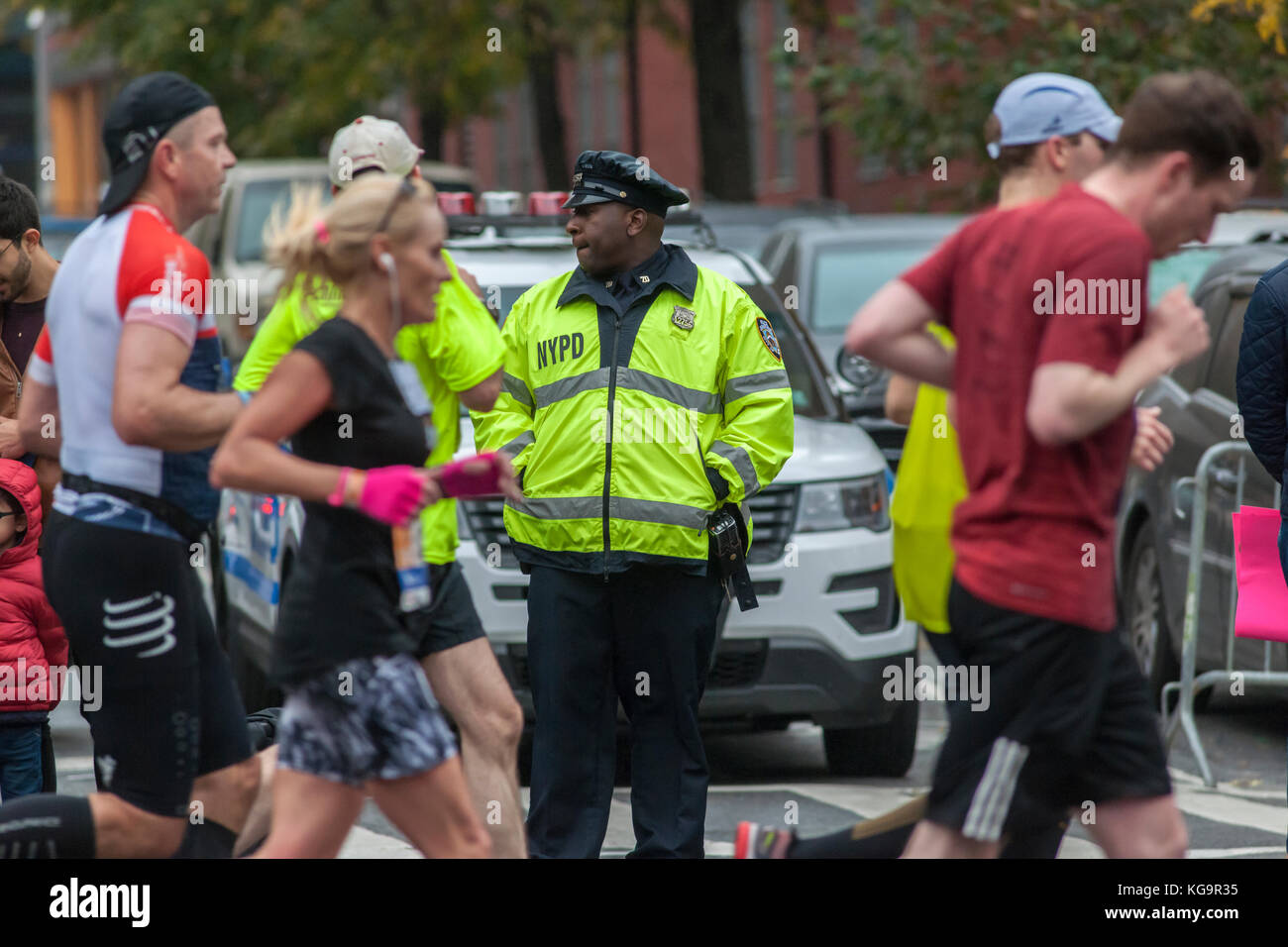 New york, Stati Uniti d'America. 05 nov, 2017. Un nypd ufficiale di servizio come corridori passano attraverso harlem in new york vicino al 22 mile mark vicino a mount morris Park domenica 5 novembre 2017 nel 47th annuale di tcs new york city marathon. circa 50.000 corridori provenienti da oltre 120 paesi sono attesi per competere in gara, la più grande del mondo di maratona. ( © richard b. levine) Credito: Richard levine/alamy live news Foto Stock