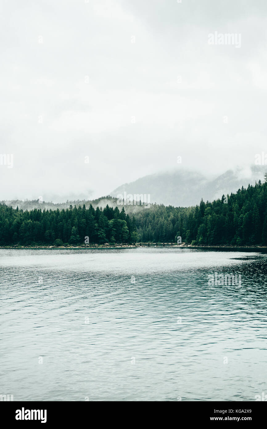 Nebbia proveniente dalla foresta circostante il eibsee lago di montagna nelle Alpi tedesche dopo la pioggia. Foto Stock