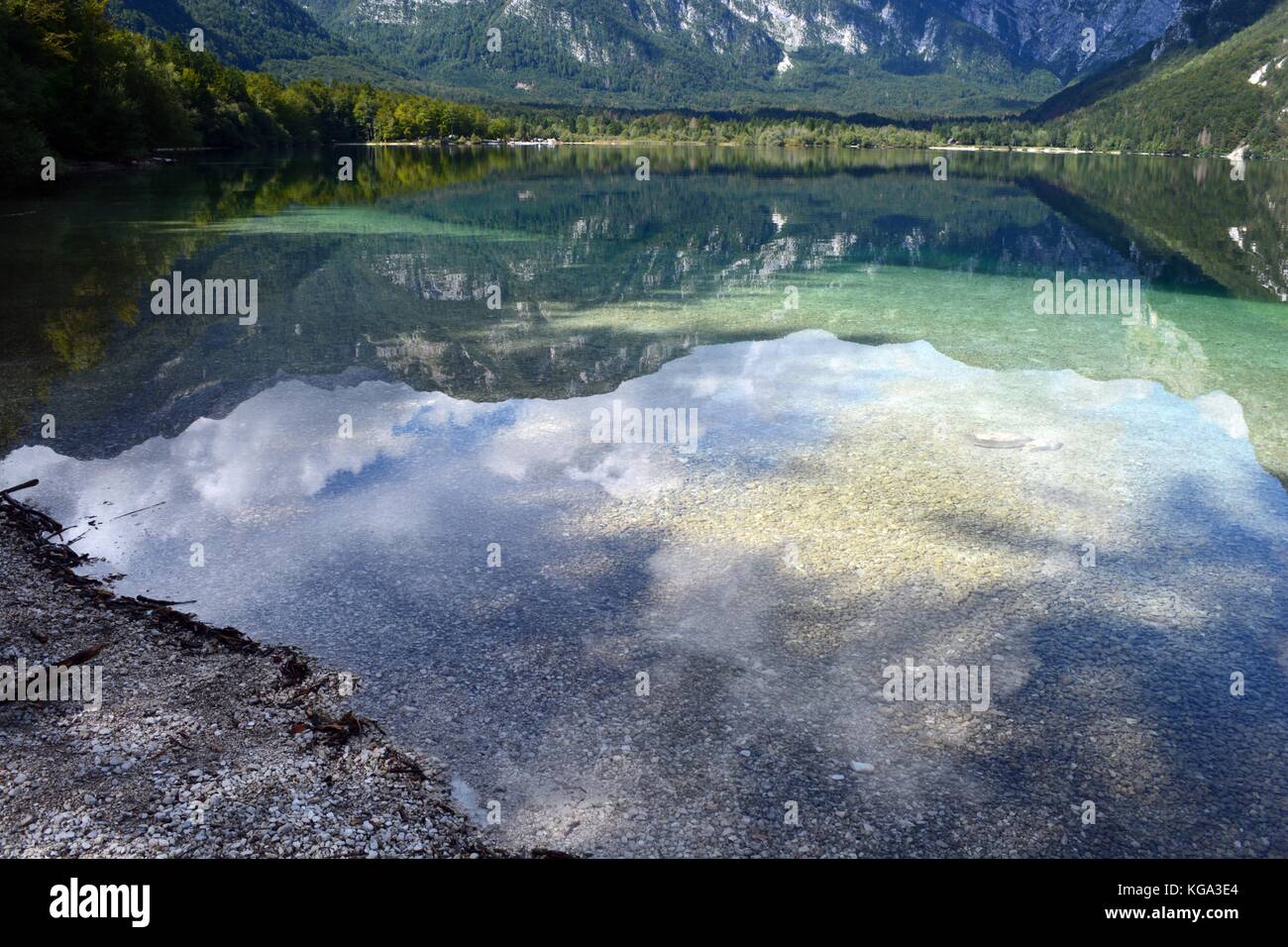 Riflessi di cielo e montagne nel lago di Bohinj, il Parco Nazionale del Triglav, Slovenia Foto Stock