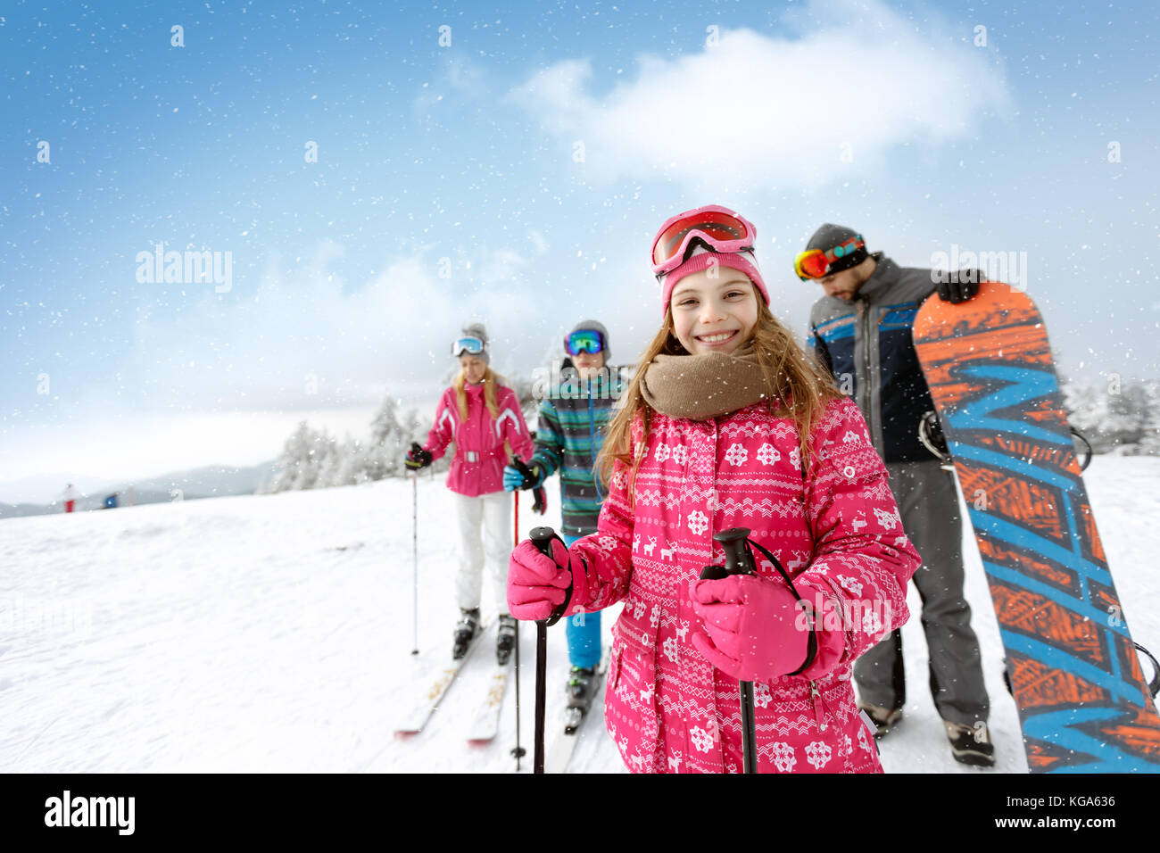 Ragazza sorridente con la famiglia sul terreno di sci pronti per lo sci Foto Stock