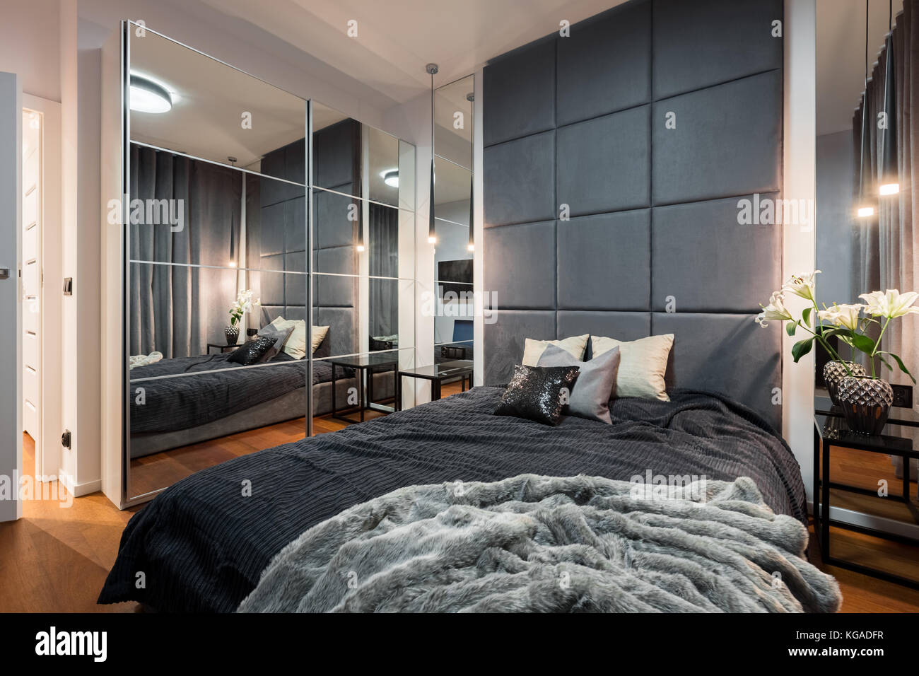 Camera da letto sofisticata con letto matrimoniale, parete imbottita e  guardaroba a specchio Foto stock - Alamy