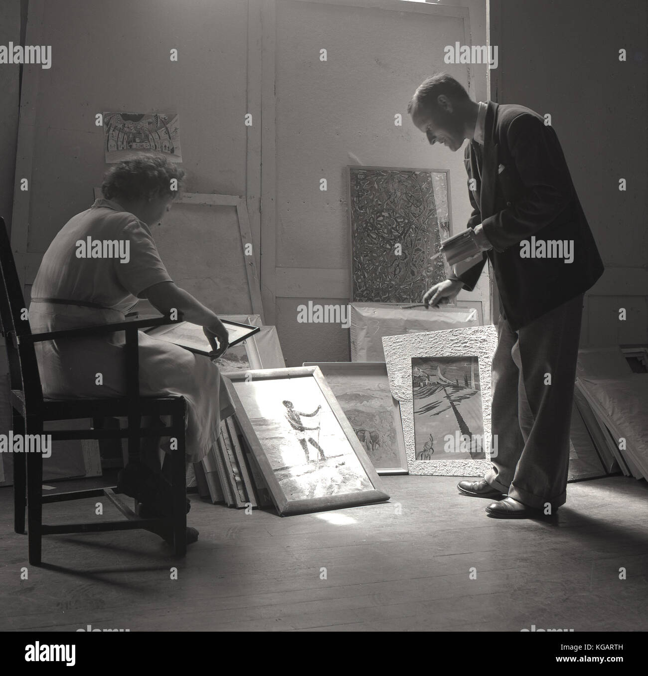Degli anni Cinquanta, foto storiche che mostra un uomo e una donna di decidere quali immagini per selezionare una galleria display. Foto Stock