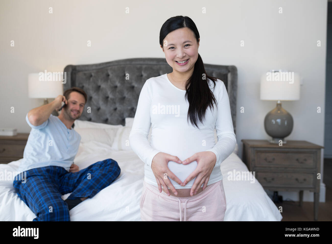 Donna felice formando forma di cuore sul ventre con le mani Foto Stock