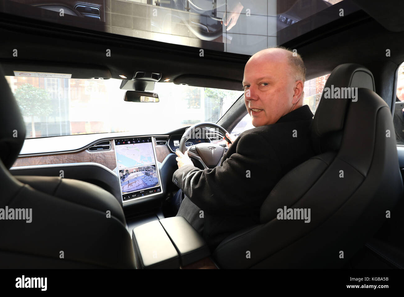Chris Grayling, Segretario dei Trasporti, dopo essere arrivato in una Tesla S car, per dare il suo discorso alla conferenza dell'Associazione degli assicuratori britannici sui veicoli autonomi presso la sede del Regno Unito a Londra. Foto Stock