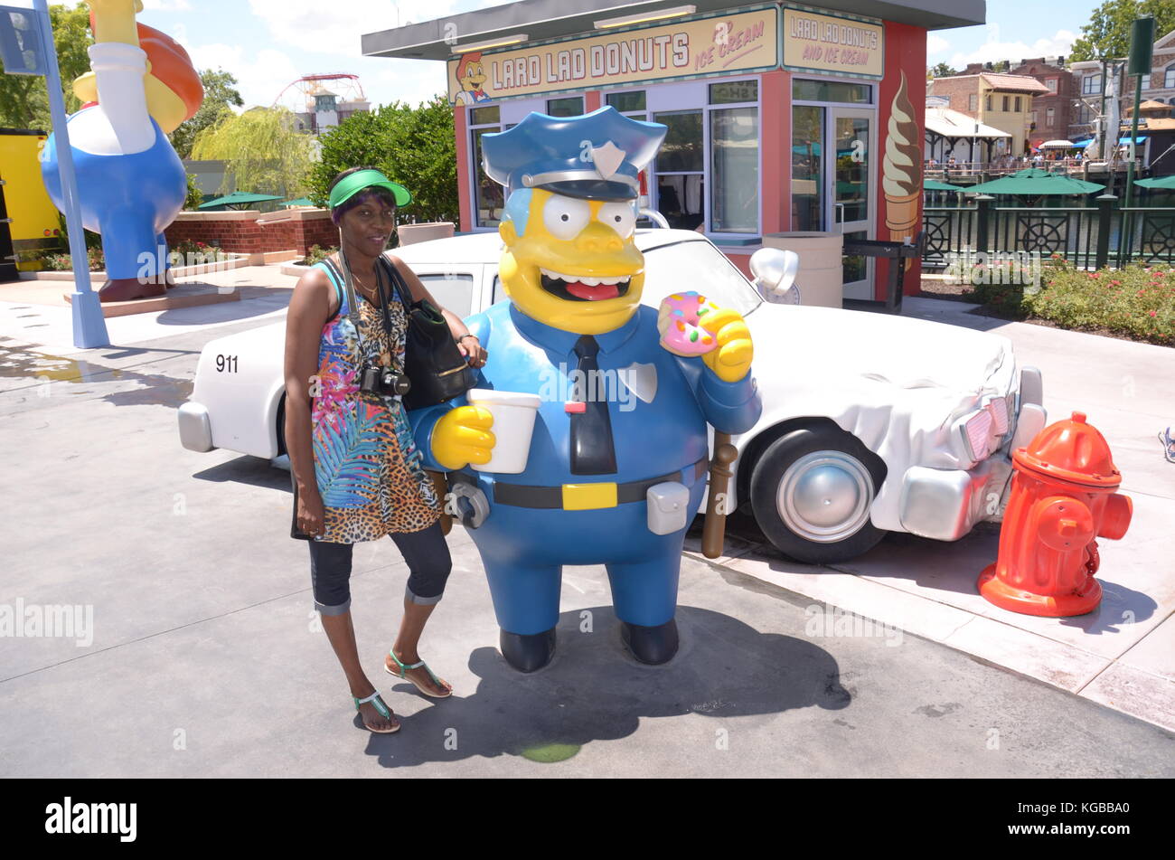 Donna afro-caraibica che posa accanto alla statua di Chief Clancy Wiggum agli Universal Studios Foto Stock