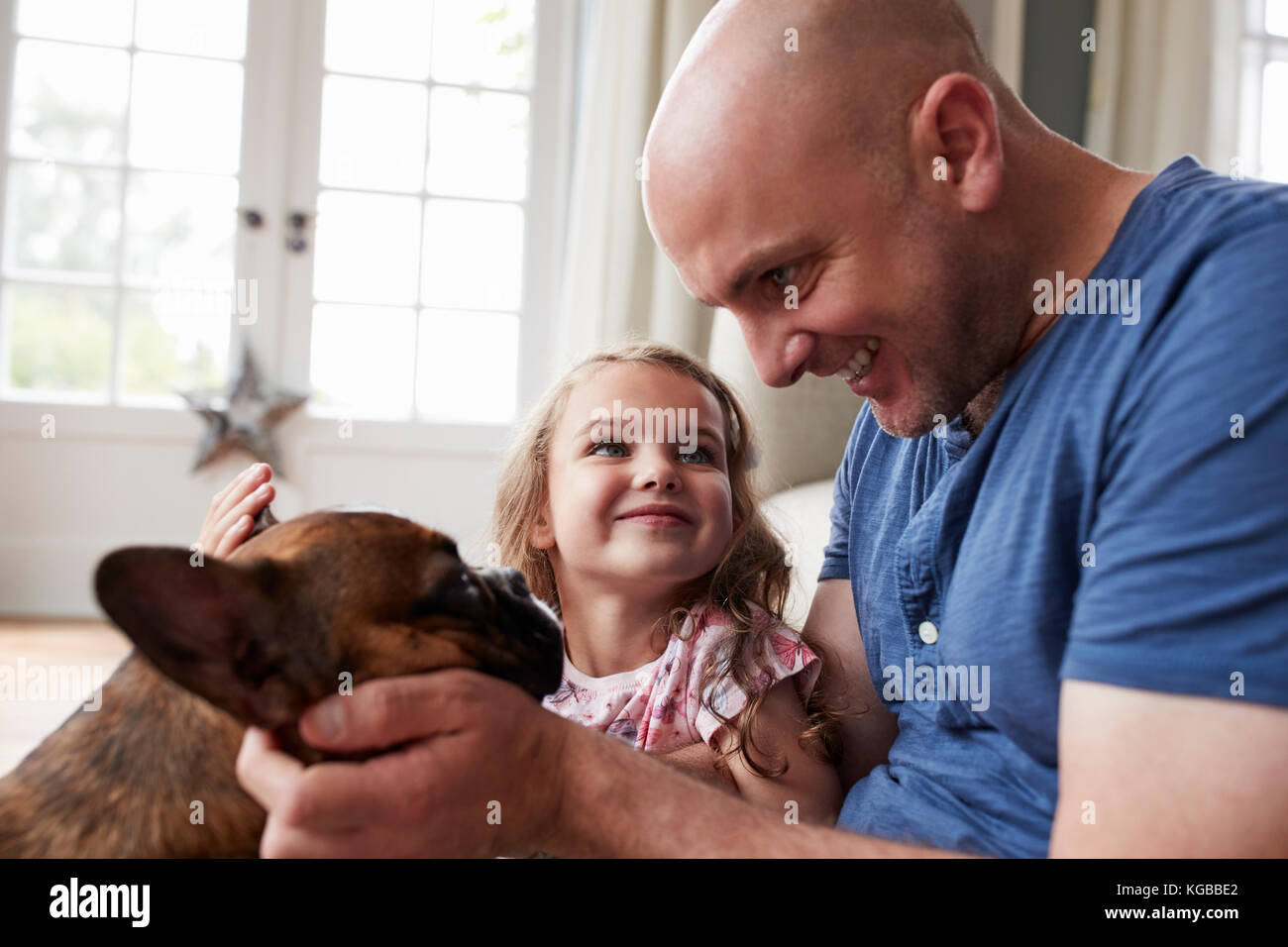 Ragazza giovane con suo padre petting cane a casa, close up Foto Stock