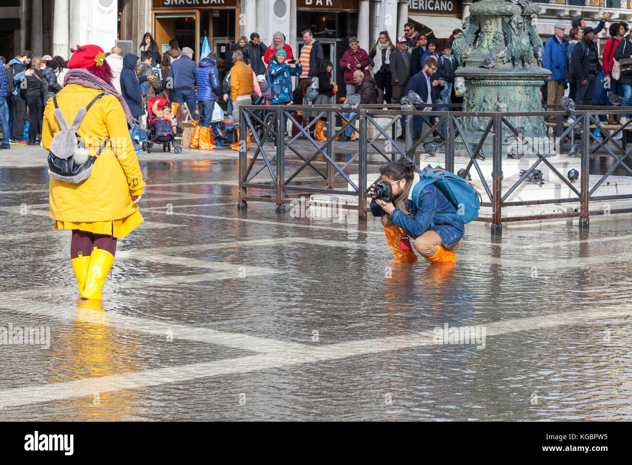 Venezia, Veneto, Italia. 6 Nov, 2017. Acqua Alta alta marea dalla laguna provocando allagamenti temporanei in Piazza San Marco. Turismo a maschio a fotografare una donna nell'acqua. Passarelle, o passerelle elevate, sono installati per il traffico pedonale. Credito: Maria Clarke/Alamy Live News Foto Stock