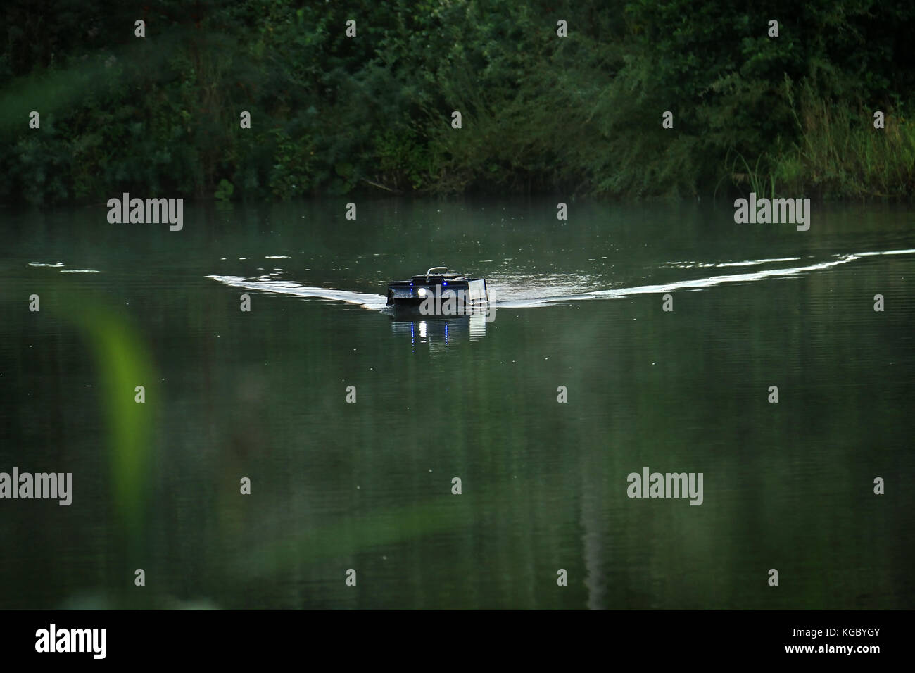 Un telecomando alimentatore controllato in barca in un lago utilizzato nella pesca sportiva. Foto Stock