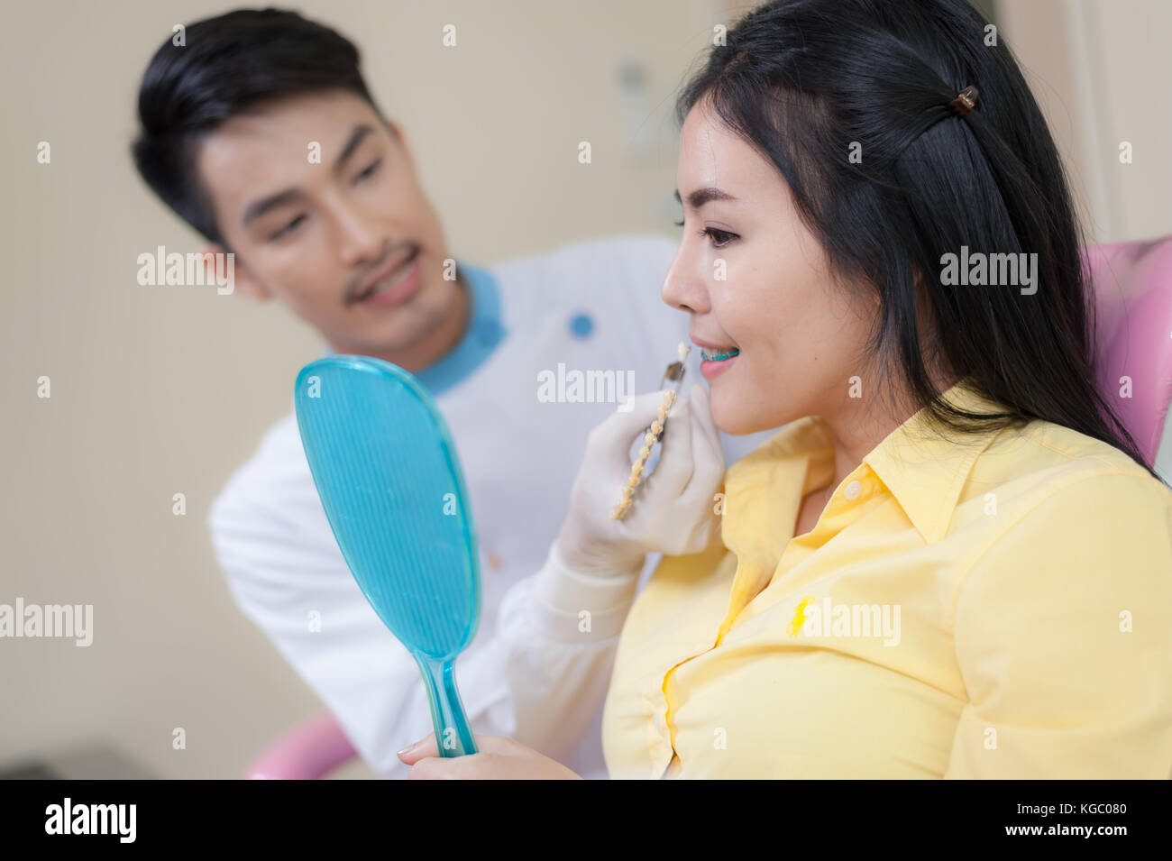 Dentista maschio spiegare circa la corona dentale al paziente di sesso femminile mentre facendo dental checkup in clinica. La somministrazione orale per la cura e la manutenzione con il concetto di esperti. Foto Stock