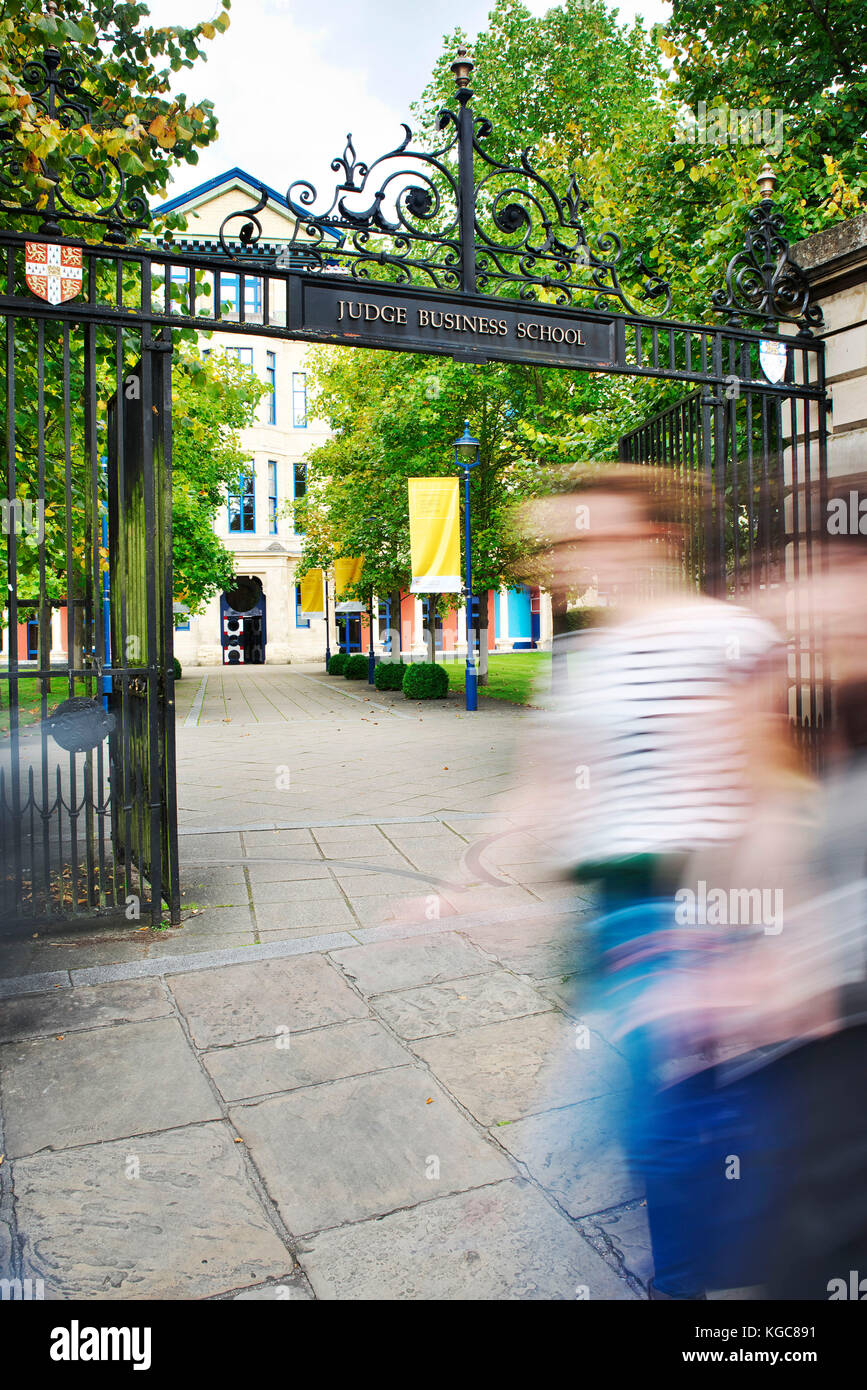 Due studenti a piedi oltre i cancelli del ben noto giudici business school di Cambridge. Le persone sono sfocate in primo piano Foto Stock