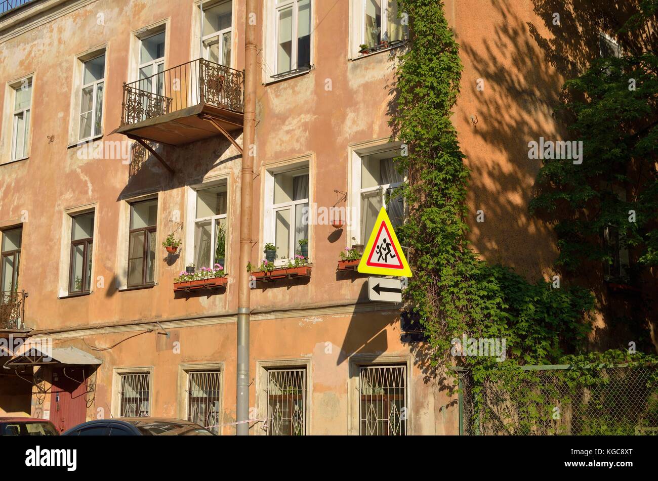 Il vecchio muro di una casa illuminata dal sole.sulla parete pende un segno. Foto Stock