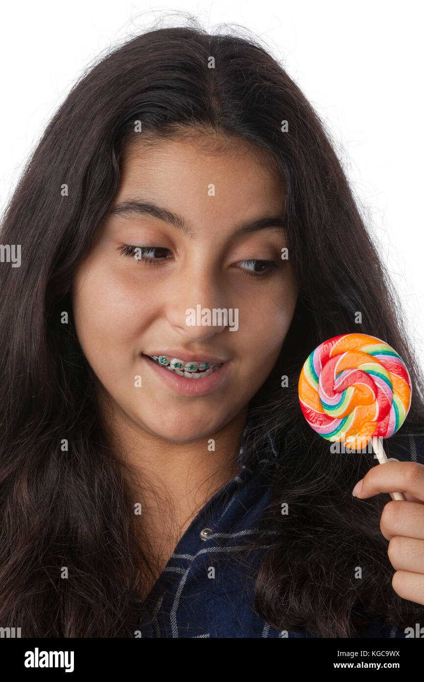 Ragazza adolescente con bretelle dentali guardando un lecca-lecca colorati Foto Stock