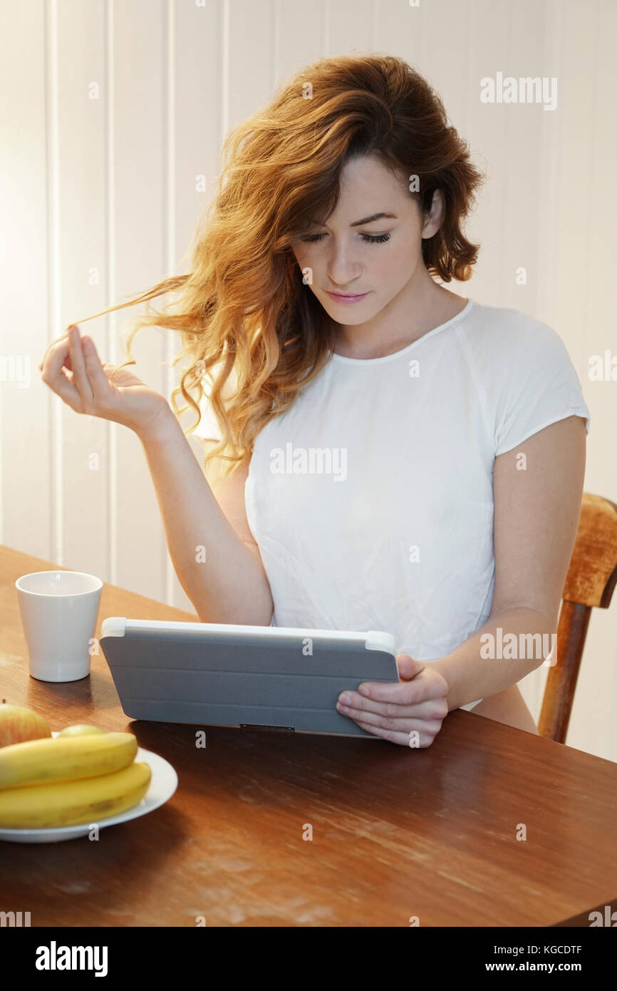 Giovane donna utilizzando tablet pc a casa Foto Stock