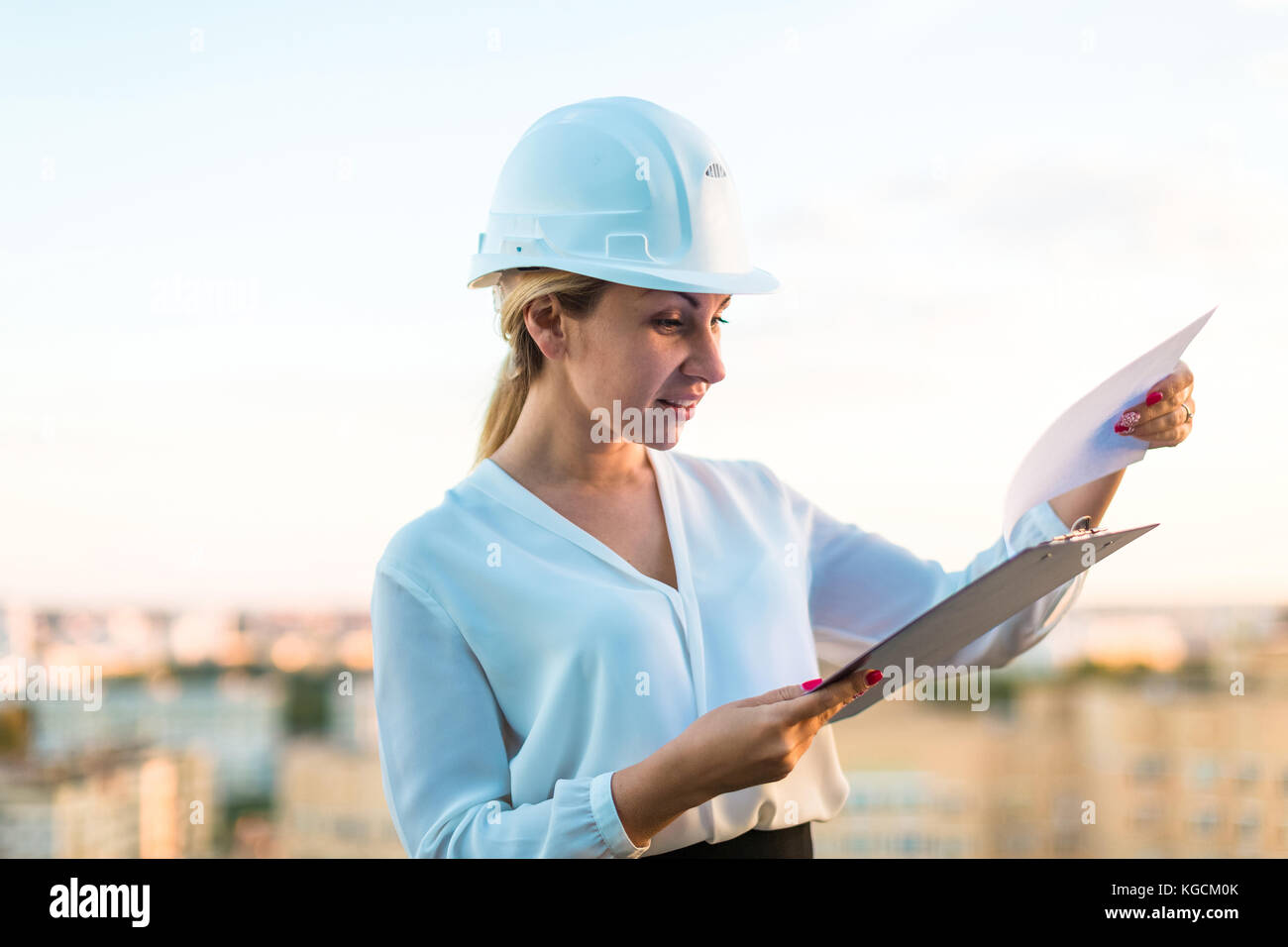 Piuttosto giovani forewoman nel casco stand sul tetto con i tablet PC Foto Stock