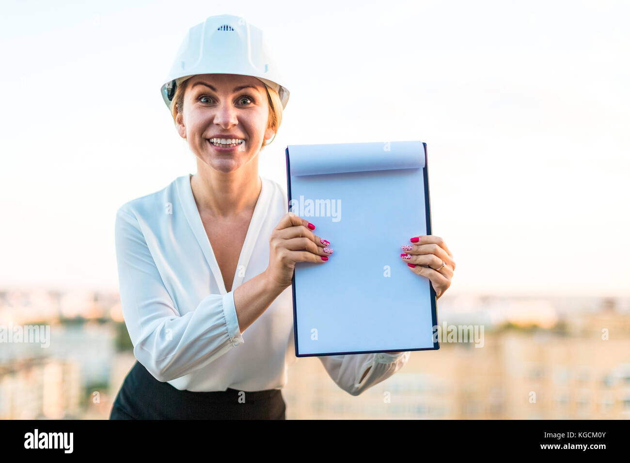 Piuttosto giovani forewoman nel casco stand sul tetto con i tablet PC Foto Stock