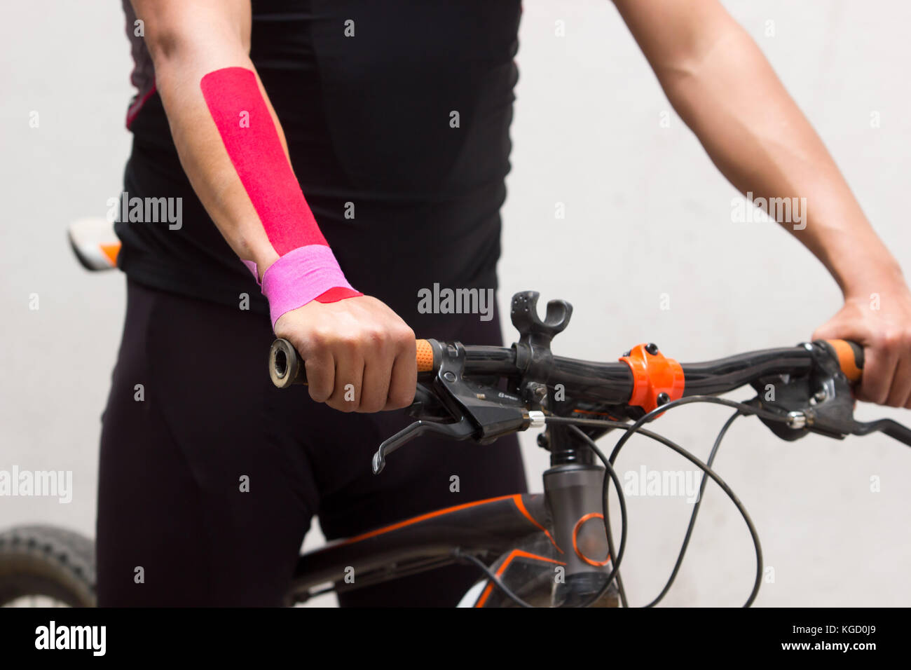 Chiudere la foto in orizzontale di un ciclista sulla sua mountain bike con kinesio nastro sul suo polso destro per ridurre il dolore Foto Stock