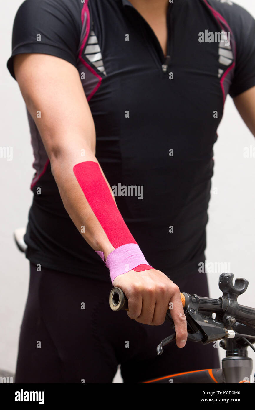 Foto verticale di un ciclista sulla sua mountain bike con kinesio nastro sul suo polso destro per ridurre il dolore Foto Stock