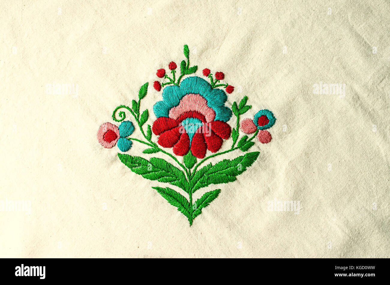 Motivo ricamato dal bouquet di fiori rosso e turchese e verde delle foglie sul tessuto di cotone Foto Stock