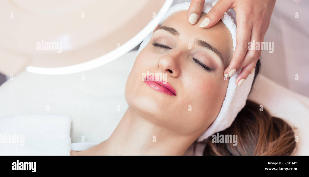 Ad alto angolo di visione del volto di un rilassato donna sorridente sotto i vantaggi di anti-invecchiamento massaggio del viso in un moderno centro di bellezza Foto Stock