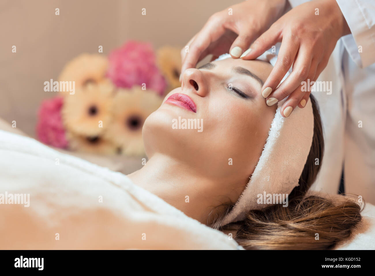 Close-up del volto di una donna bella rilassante sotto la carezza del terapeuta, durante il massaggio ringiovanente del viso in una bellezza moderna cento Foto Stock