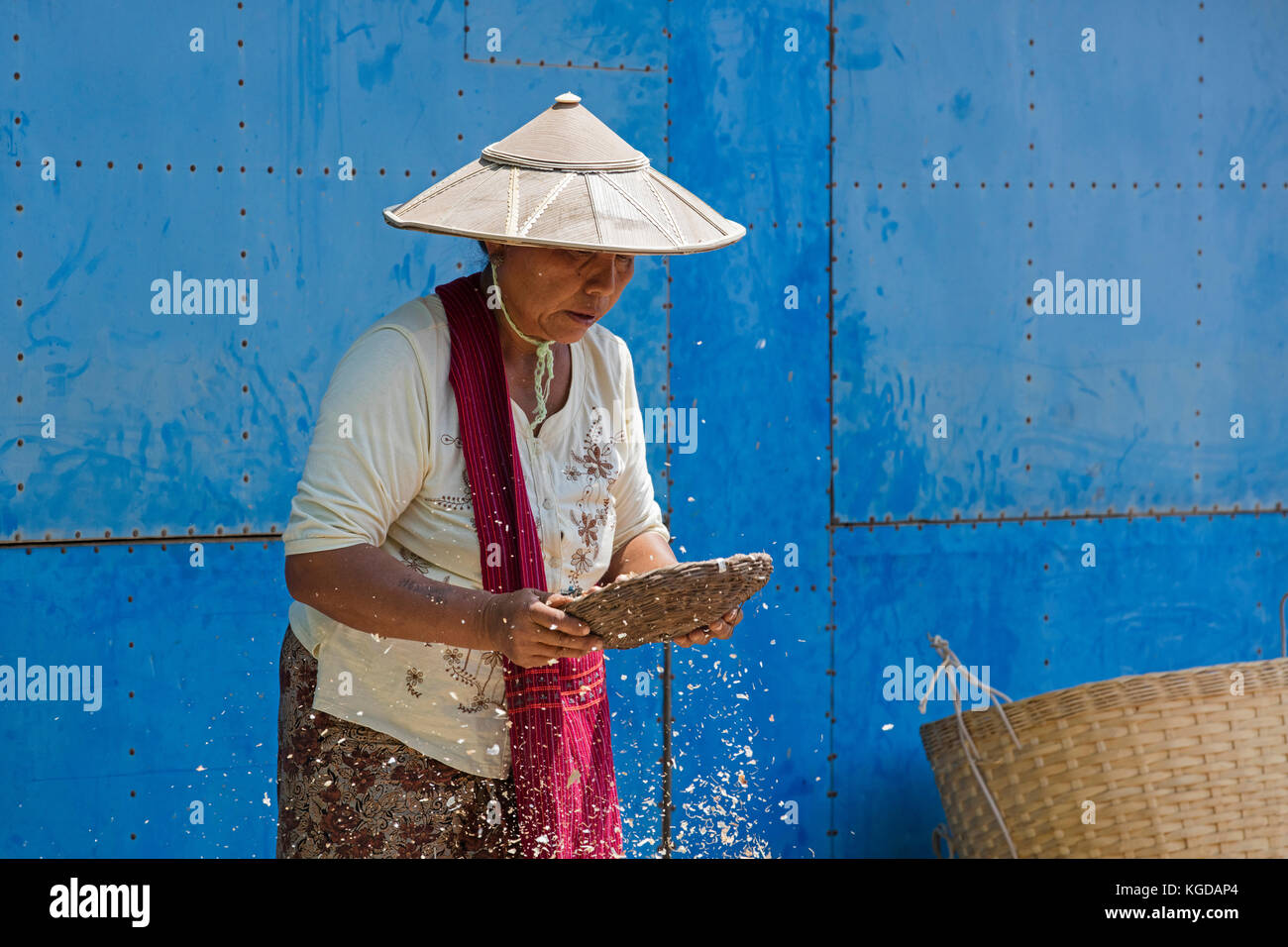 Donna birmano indossando il tradizionale bambù hat setacciatura di cibo nel villaggio lungo Lago Inle, nyaungshwe, stato shan, myanmar / BIRMANIA Foto Stock