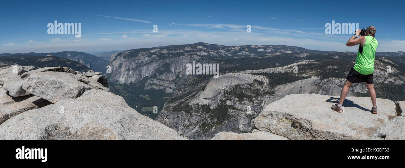 Un uomo prende le foto dal bordo sulla parte superiore di half dome nel parco nazionale di Yosemite. Foto Stock