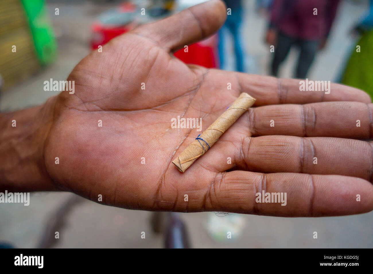 Delhi, India - 25 settembre 2017: close up di una mano di un uomo con una foglia di sigarette incartati a mano, nelle strade di paharganj new delhi india Foto Stock