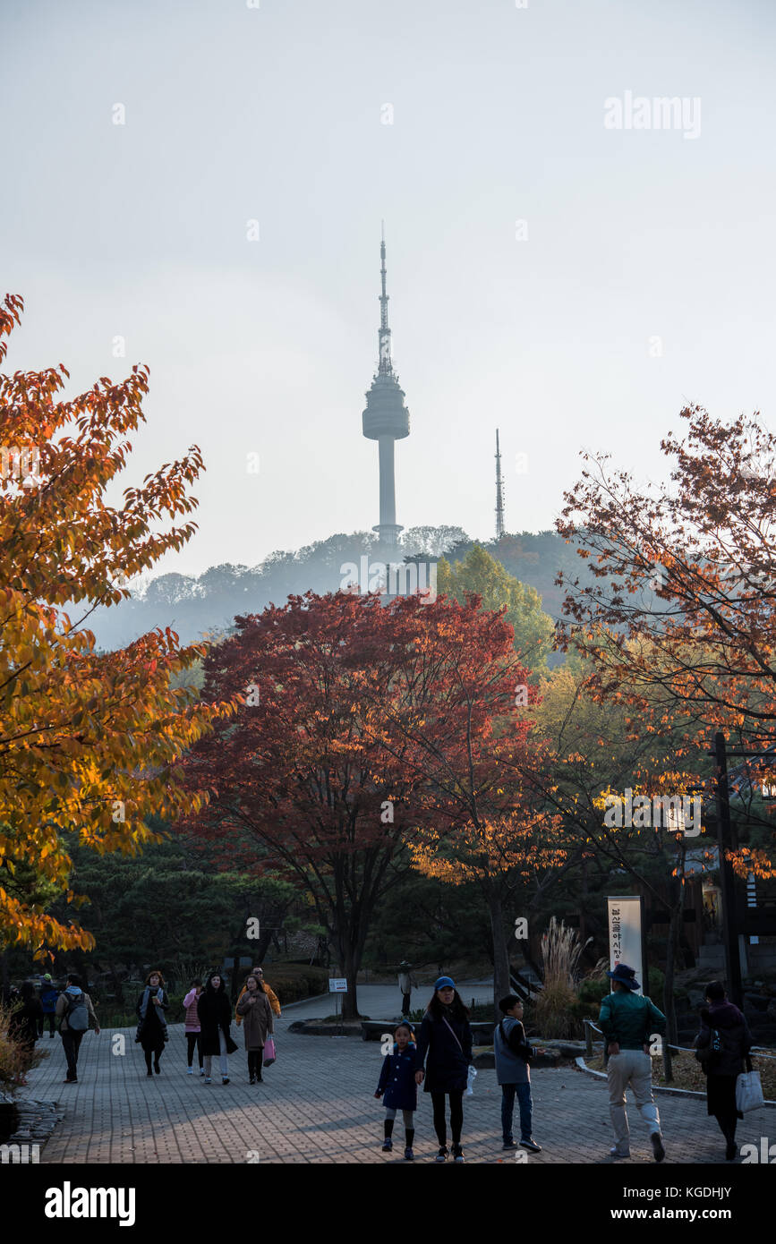 Alberi dai colori autunnali con gente coreana in primo piano e vista sulla Seoul N Tower sullo sfondo Foto Stock