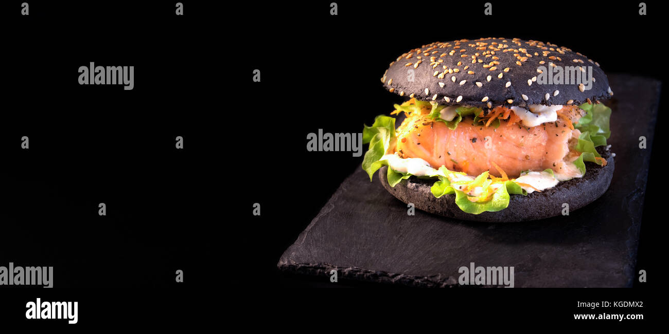 Deliziosi hamburger di nero con salmone alla griglia sulla piastra di  ardesia e sfondo nero. copia di spazio Foto stock - Alamy