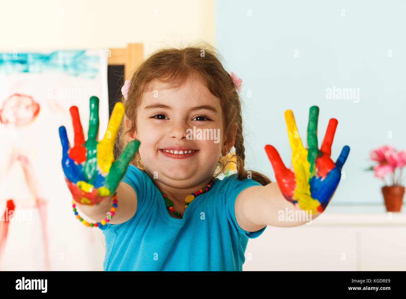 Bambina di cinque anni con le mani dipinte di vernici colorate pronti per le stampe a mano Foto Stock