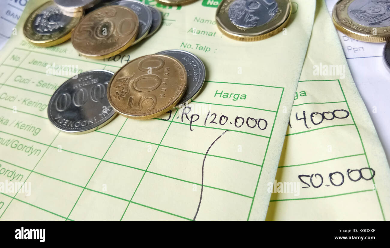 Calcolo della ricevuta di pagamento con rupia indonesiana, monete in dollari di Singapore e fatture scritte a mano Foto Stock