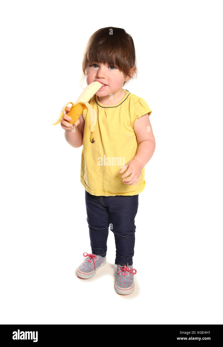 2 anno di età bambino mangiare una banana in un studio Foto Stock