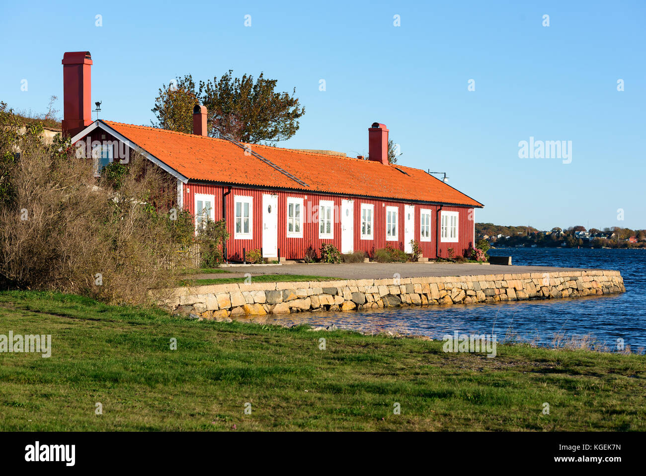 Karlskrona, Svezia - 30 ottobre 2017: Documentario sulla vita quotidiana e sull'ambiente. Edificio di appartamenti di colore rosso e bianco sul mare con molo in pietra davanti Foto Stock