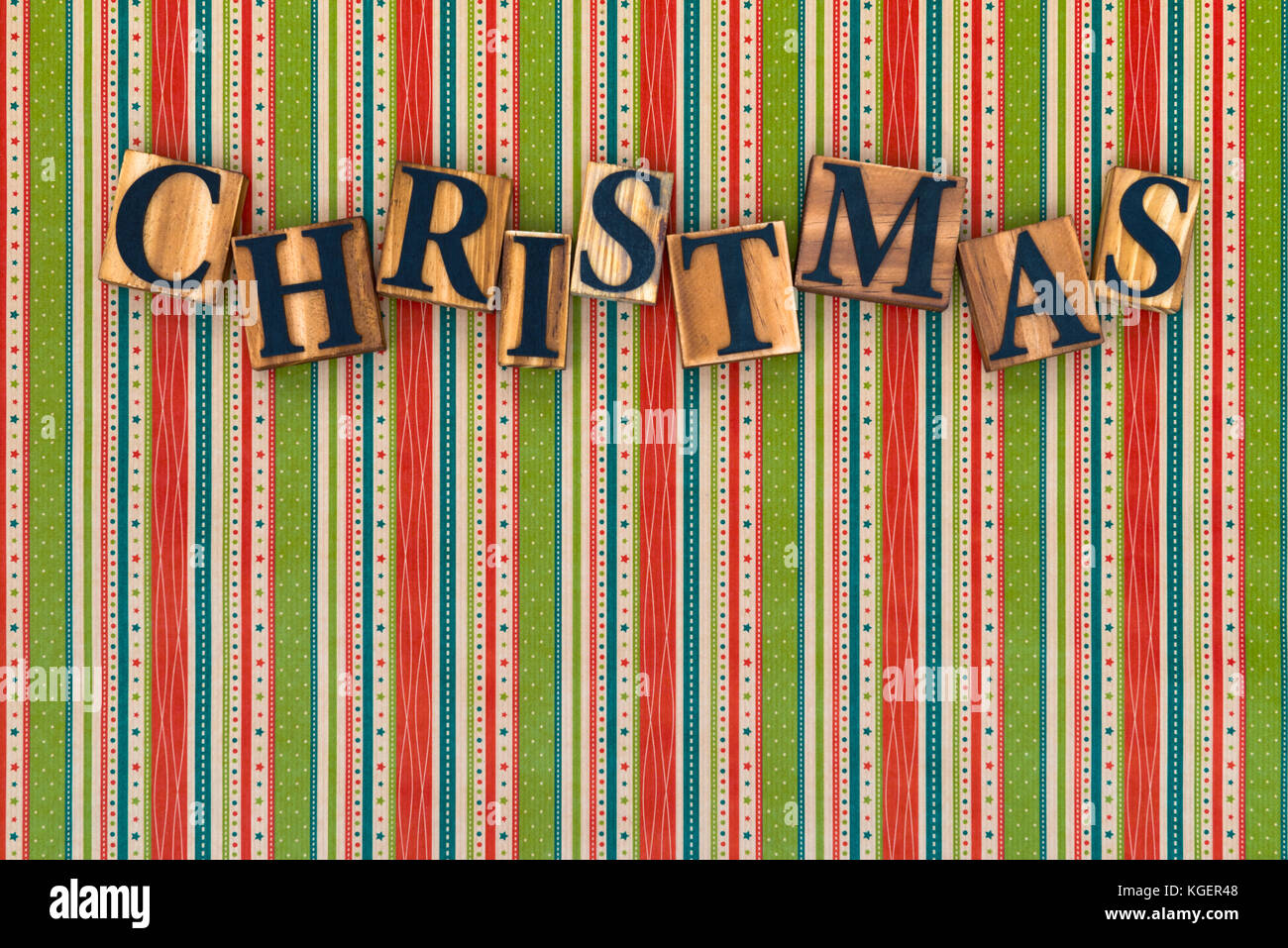 La parola Natale fatti da lettere di legno su una festa a strisce dello sfondo. Foto Stock