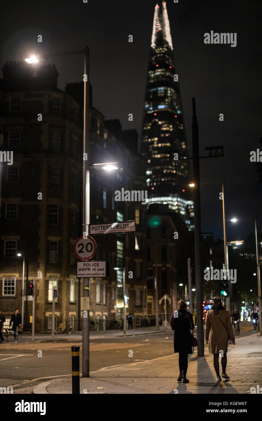 Due persone a piedi giù per la strada di Londra con shard in background Foto Stock