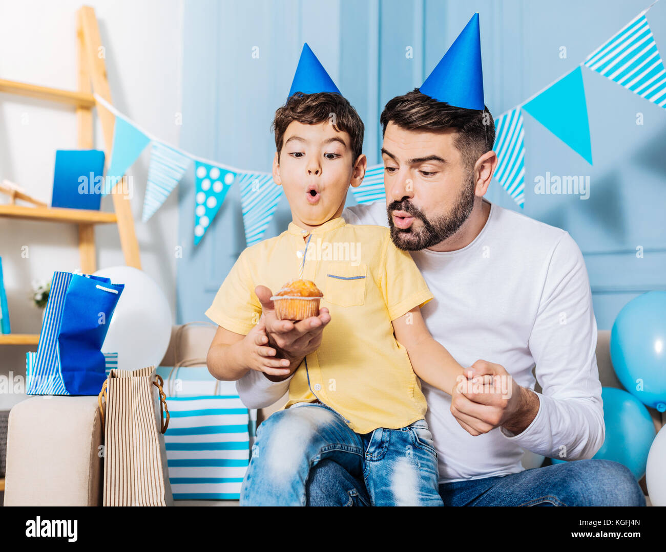 Padre piacevole aiutare piccolo figlio di soffiare la candela di compleanno Foto Stock